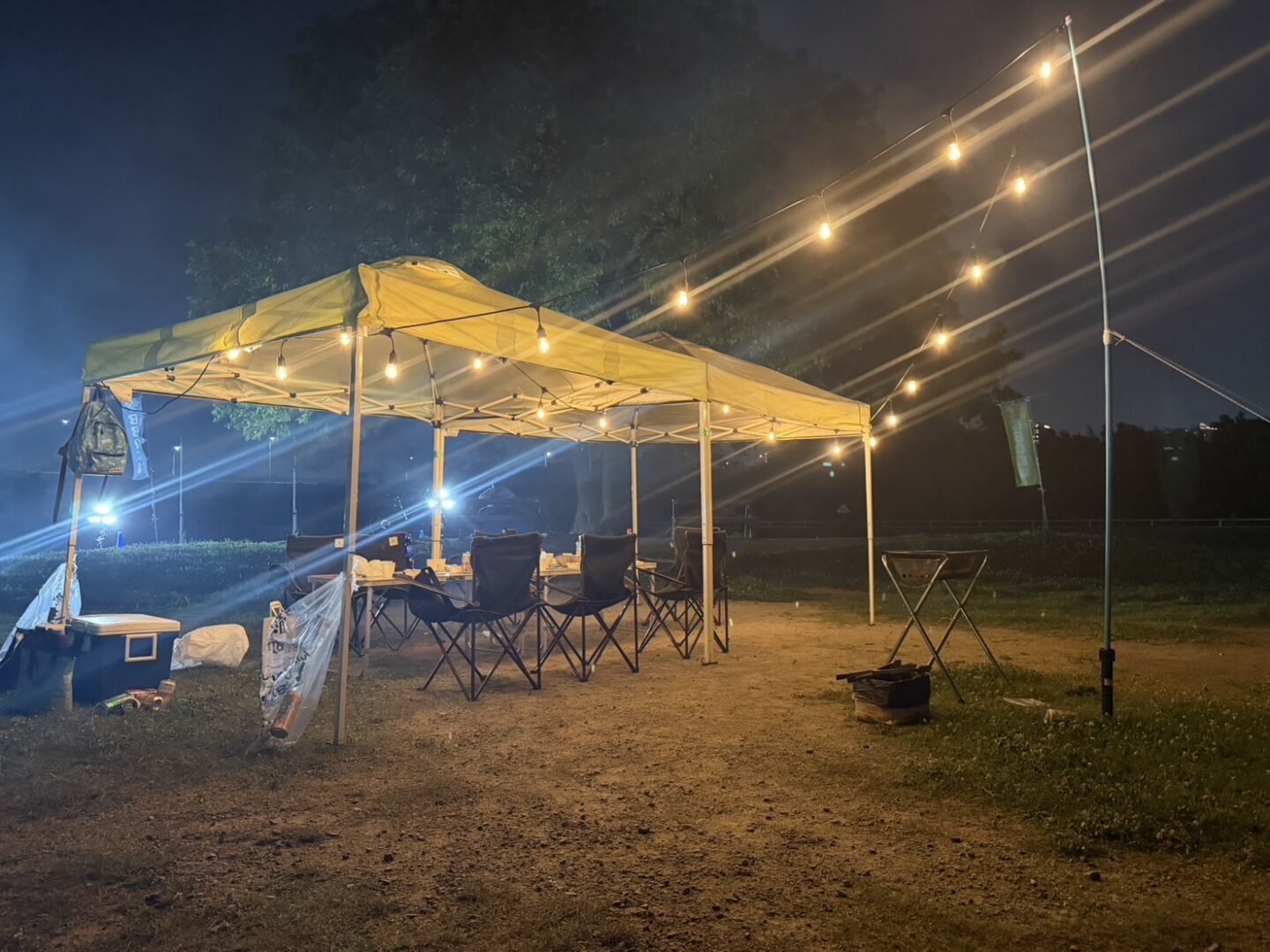 電球の明かりに照らされた西中島ナイトBBQのテントとテーブル